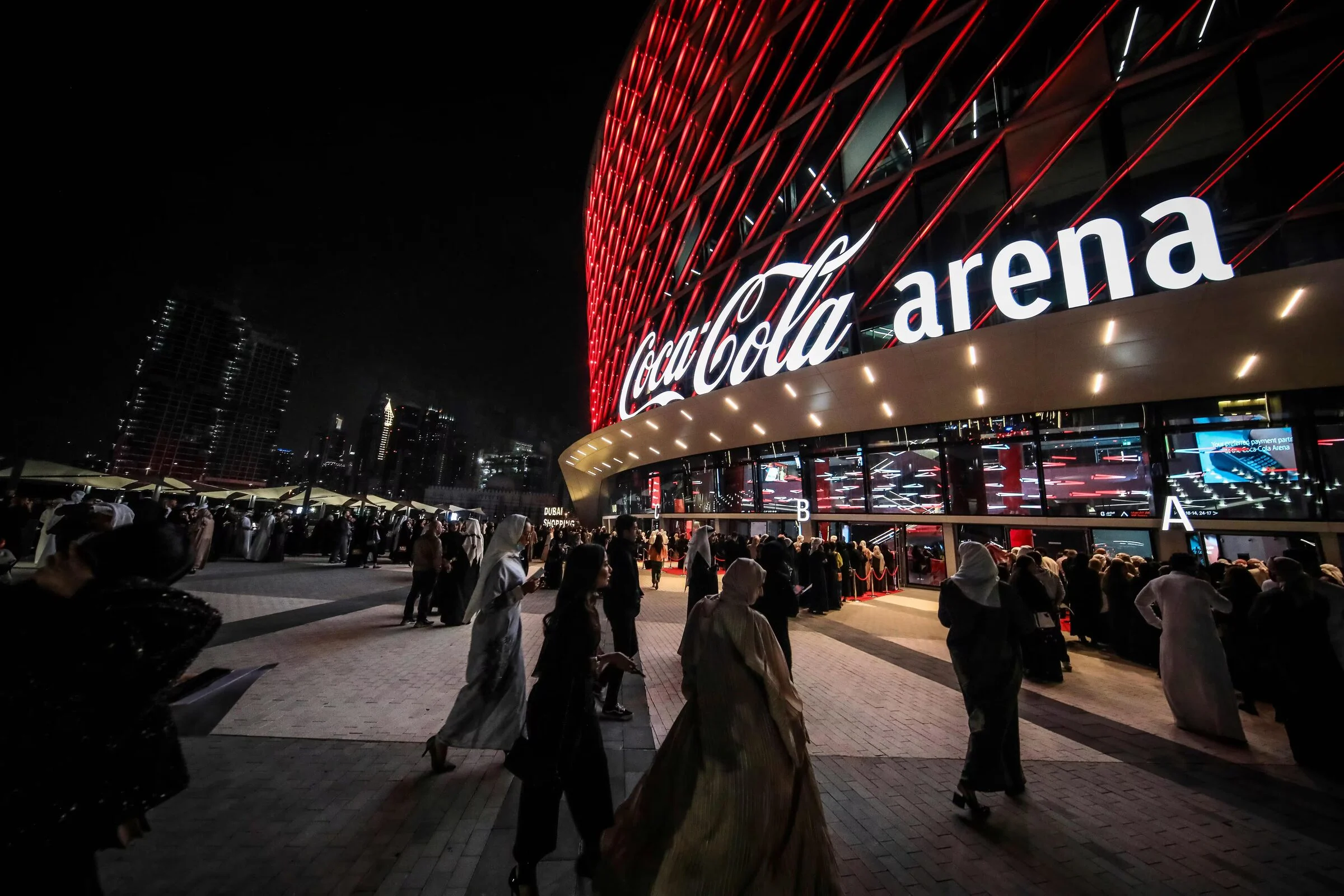 Coca-Cola Arena in Dubai lit in red at night with guests arriving