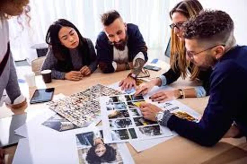 A creative team reviewing printed photographs around a table