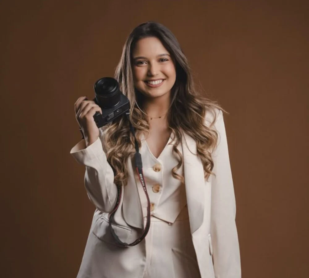 A woman holding a camera in a warm studio