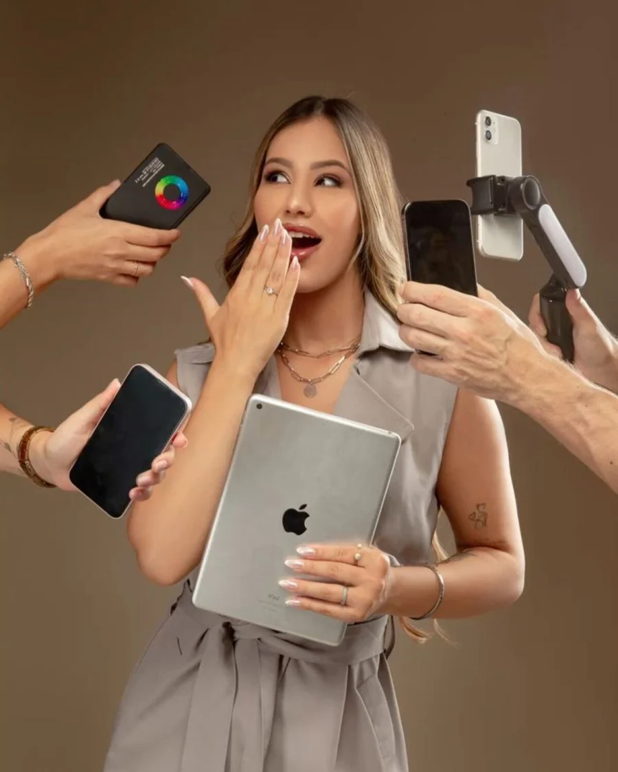 A woman holding several phones and a tablet in a creative studio